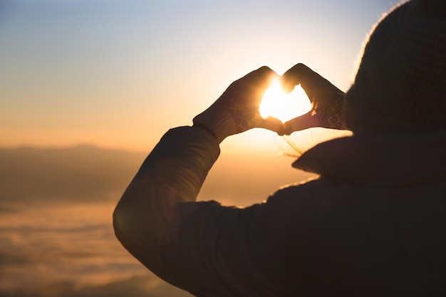 写真 夕暮れの時に太陽を抱いている男性のシルエット