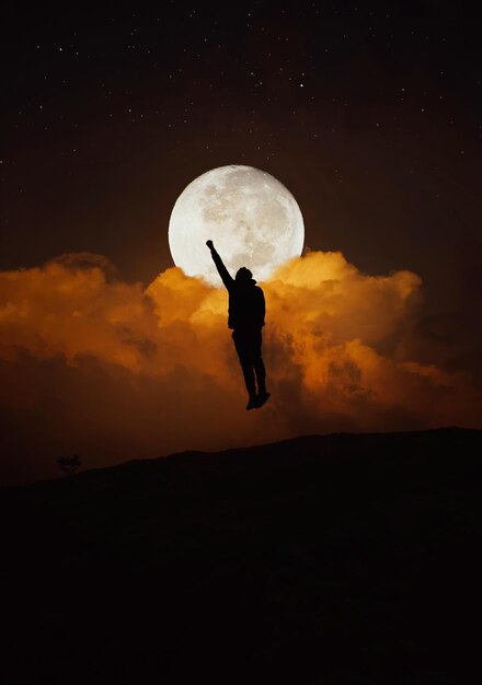 Foto l'uomo silhouette che salta contro la luna di notte