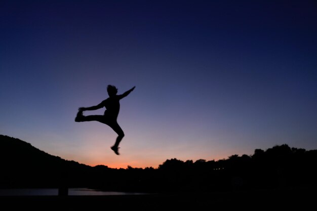 Photo silhouette man jumping against orange sky