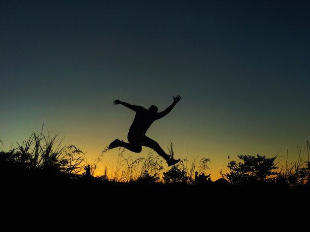 Силуэт человека, прыгающего на небо во время захода солнца