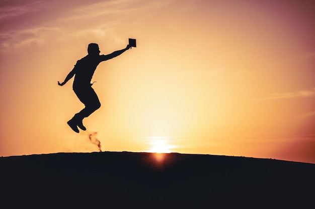 Silhouette man jumping against sky during sunset