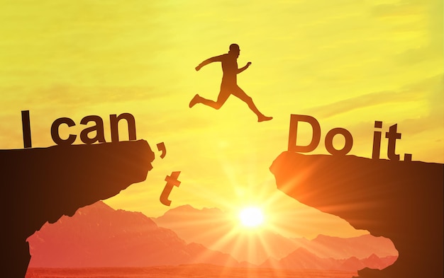 Photo silhouette of man jumping and change i can't do it to i can do it text on mountain sky and sun light background motivation business success achievement and idea concept