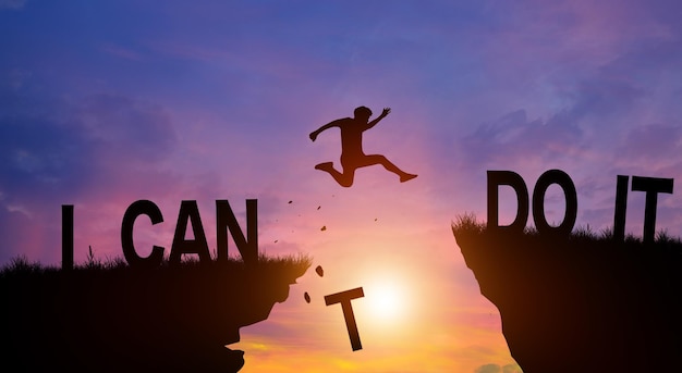 Silhouette man jumping over the cliffs with I can do it word in sunlight Never give up Good mindset Concept