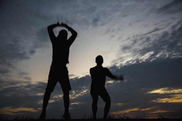 夕日に幸せとジャンプする男のシルエット。