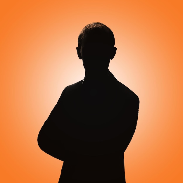 Photo silhouette of a man man posing in a suit on an orange background