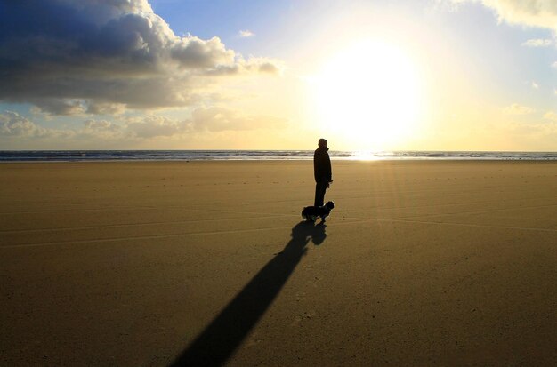 写真 夕暮れの空に照らされたビーチのシルエット男