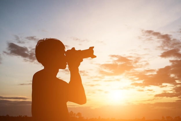 写真 夕暮れの空を照らして写真を撮るシルエットの男性