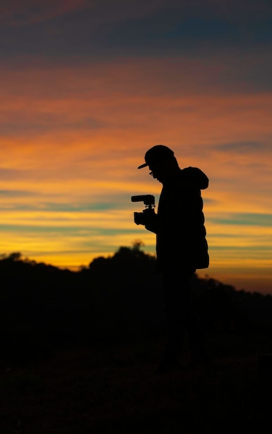 Photo silhouette man photographing against sky during sunset