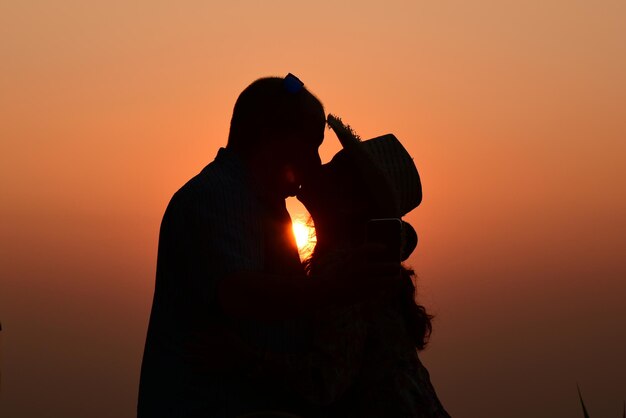 Silhouette man photographing against sky during sunset