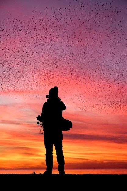 Photo silhouette man photographing against sky during sunset