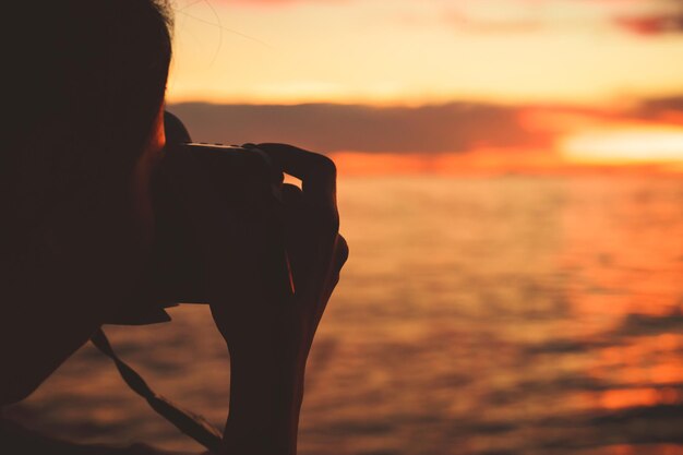 Foto uomo a silhouette che fotografa contro il cielo durante il tramonto.