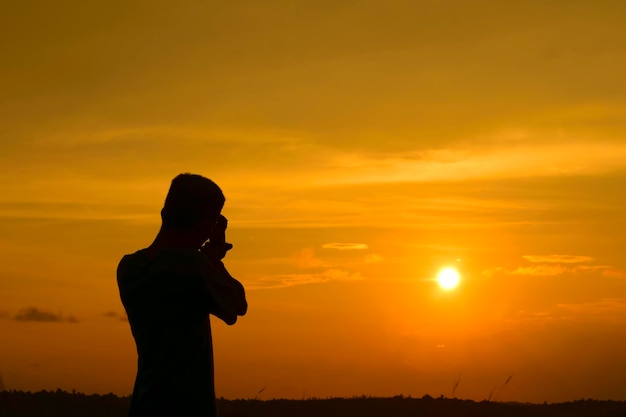 静かな夕暮れを撮影するシルエットの男