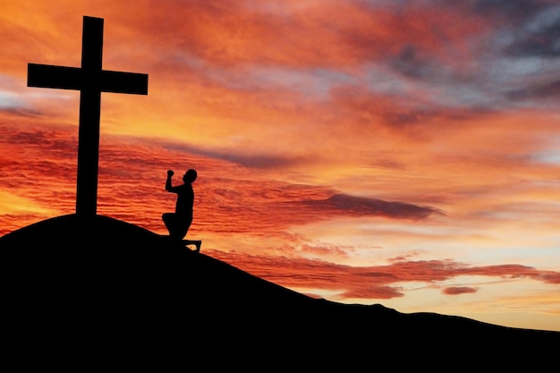 Photo silhouette of a man praying under the cross