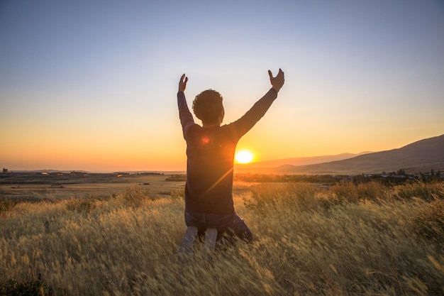 Silhouette of man praying at the sunsetxA