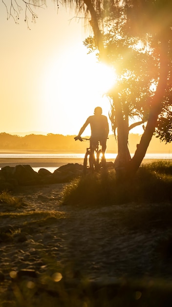 Silhouette of Man Ride a Bicycle at the Coast in Summer at Sunset Background in Noosa Australia