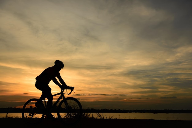 夕日に自転車に乗る男のシルエット