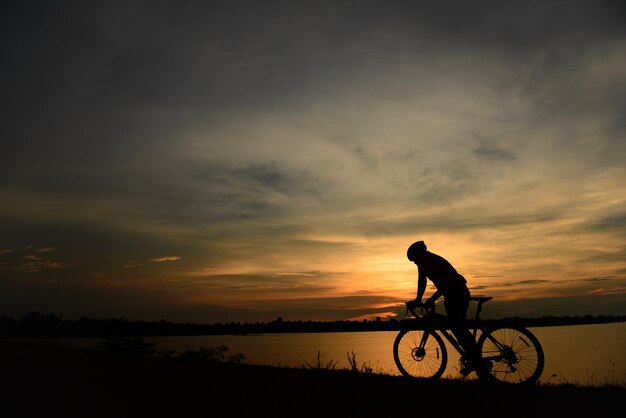 夕日に自転車に乗る男のシルエット