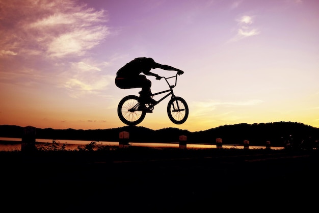 silhouette of man riding a bmx bicycle