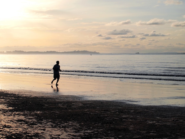 Silhouette of a man running in the beach during sunset 