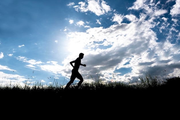 Silhouette man running on field against sky