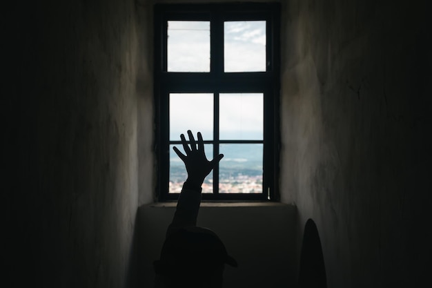 Silhouette of a man's hand on the background of a vintage castle window with view of mountains town