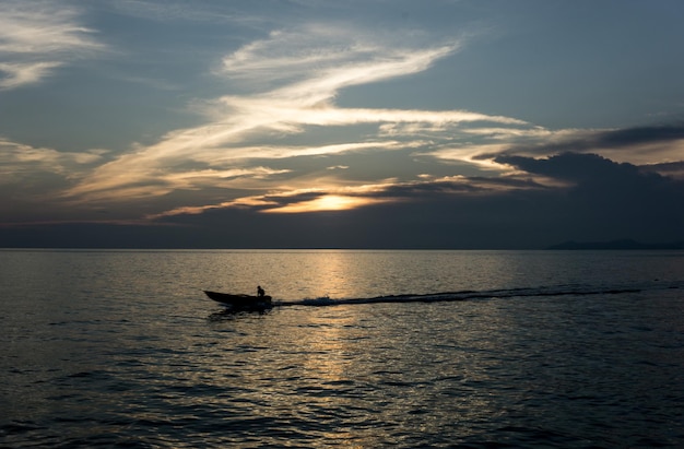 夕暮れの空に照らして海に映る男性のシルエット