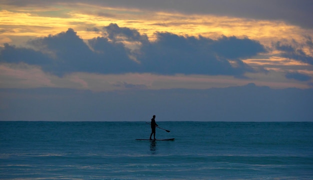 夕暮れの空を背景に海に描かれた男のシルエット