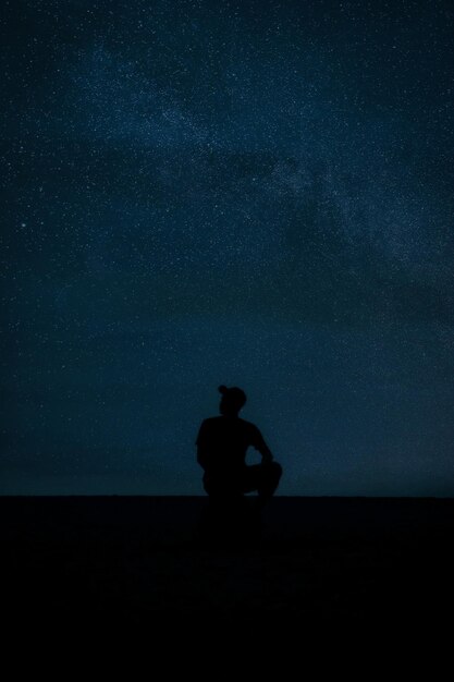 Foto silhouette uomo seduto contro il cielo di notte