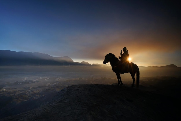 Foto silhouette uomo seduto a cavallo sopra la montagna