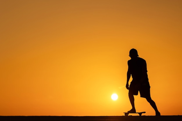 Silhouette of a man skating on skateboard at sunset