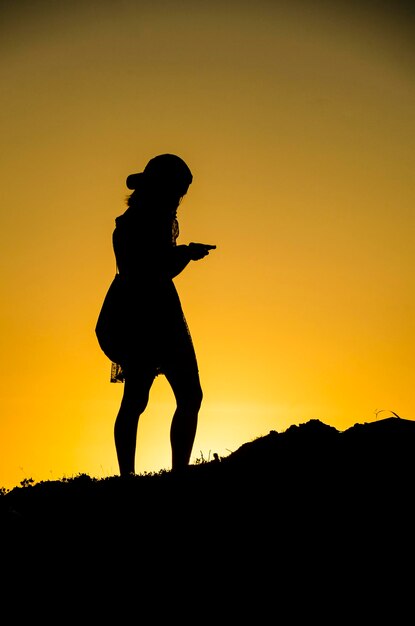 Foto l'uomo silhouette in piedi contro il cielo arancione