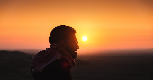 Photo silhouette of man standing against orange sky