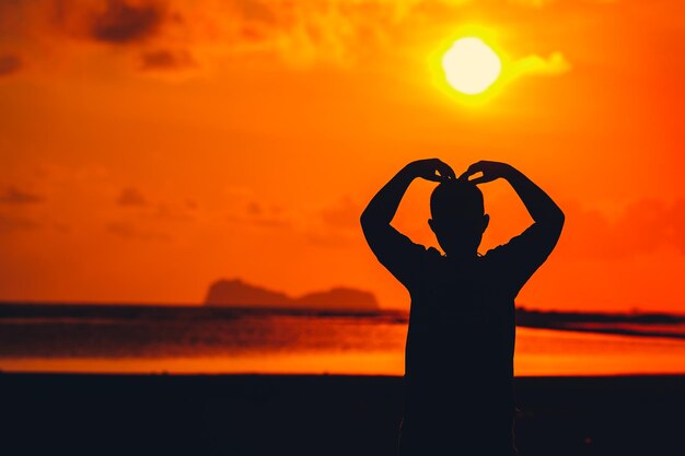 Foto l'uomo silhouette in piedi contro il cielo arancione