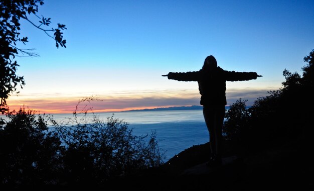 사진 해가 지는 동안 하늘을 향해 서 있는 실루 남자