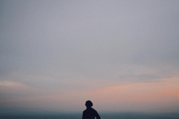 夕暮れの空に向かって立っている男性のシルエット