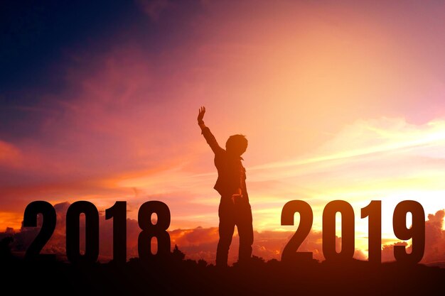 Silhouette man standing amidst numbers on field against orange sky