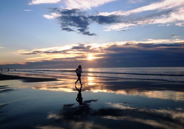 Silhouette man standing on beach against sky during sunset