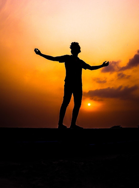 Photo silhouette man standing on beach against sky during sunset