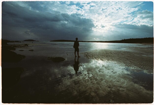 Foto silhouette uomo in piedi sulla spiaggia contro il cielo