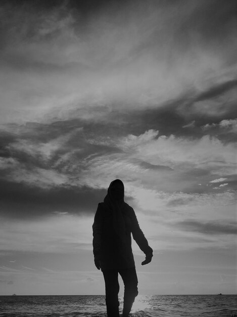 Silhouette man standing on beach against sky