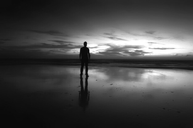 Foto silhouette uomo in piedi sulla spiaggia contro il cielo