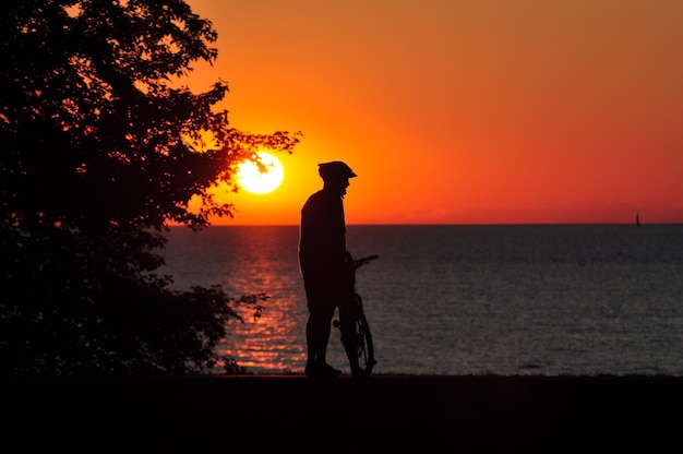 Foto silhouette di un uomo in piedi sulla spiaggia durante il tramonto