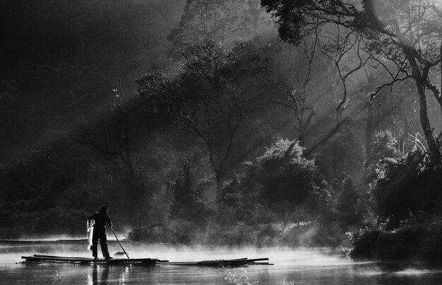 Foto uomo a silhouette in piedi vicino al lago contro gli alberi