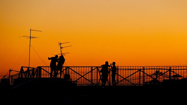 Foto silhouette uomo in piedi dalla ringhiera contro il cielo arancione