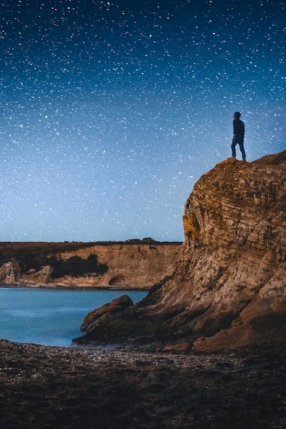 Foto silhouette uomo in piedi su una scogliera contro il cielo di notte