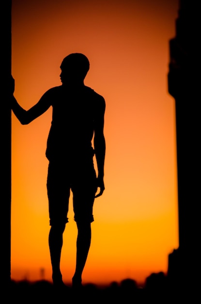 Foto silhouette uomo in piedi sul campo contro il cielo arancione