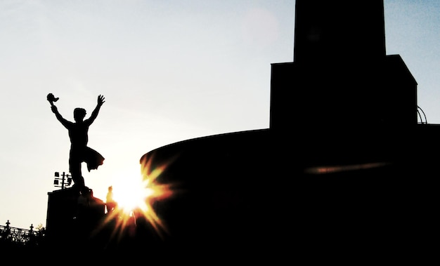 写真 夕暮れの空に向かって公園に立っているシルエットの男