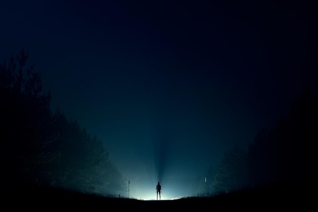 Photo silhouette man standing on land against sky at night