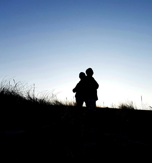 Photo silhouette of man standing on landscape against clear sky at sunset