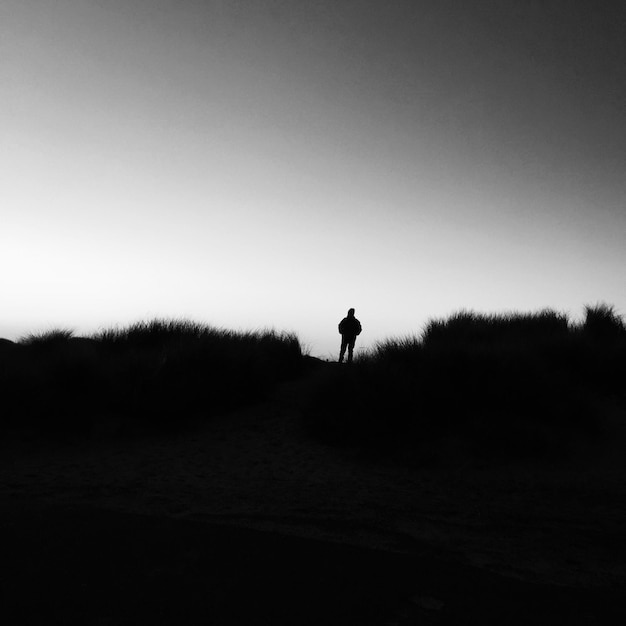 Silhouette man standing on landscape against clear sky